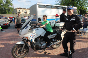 Na zdjęciu widoczny jest chłopiec siedzący na motocyklu razem z policjantem z Wydziału Ruchu Drogowego pruszkowskiej komendy