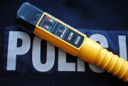 Na zdjęciu na tle napisu POLICJA widoczne jest urządzenie alcoblow koloru żółtego, służące do pomiaru zawartości alkoholu w wydychanym powietrzu.