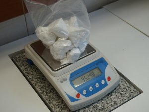 Na zdjęciu widoczna jest waga laboratoryjna, na której lezy torba foliowa z zawartością białej zbrylonej substancji (amfetaminy).