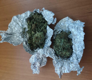 Na zdjęciu widoczne są dwa zawiniątka z folii aluminiowej koloru srebrnego z zawartością suszu roślinnego marihuany
