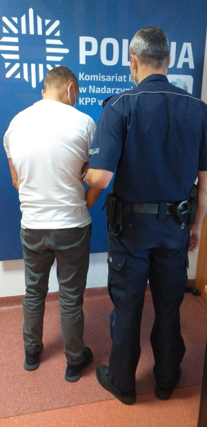 Na zdjęciu widoczny jest policjant, który trzyma zatrzymanego za kradzieże mężczyznę.