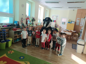 Policyjny borsuk na zdjęciu z grupą najmłodszych przedszkolaków.
