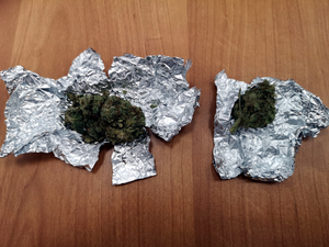 Na zdjęciu  widoczne są dwa zawiniątka z folii aluminiowej z zawartością suszu roślinnego koloru zielonego -marihuana