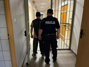 umundurowany policjant z zatrzymanym mężczyzną