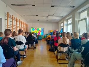 policjantka podczas spotkań profilaktycznych, widoczni uczniowie siedzący na krzesłach, słuchający umundurowanej policjantki