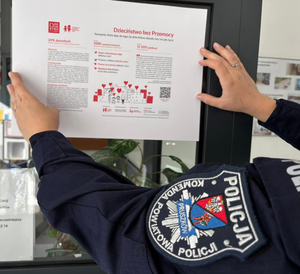policjantka przyklejająca plakat na szybę