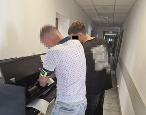 policjant wykonujący czynności z zatrzymanym mężczyzną